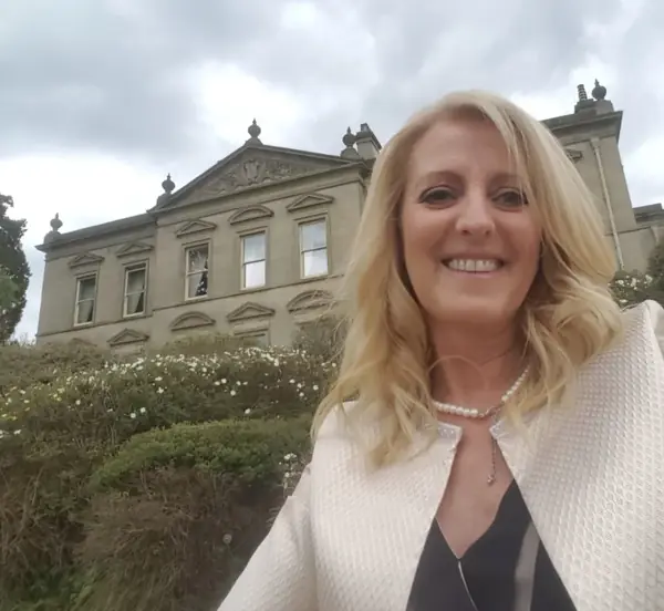 Hayley the celebrant smiling in front of a grand country house